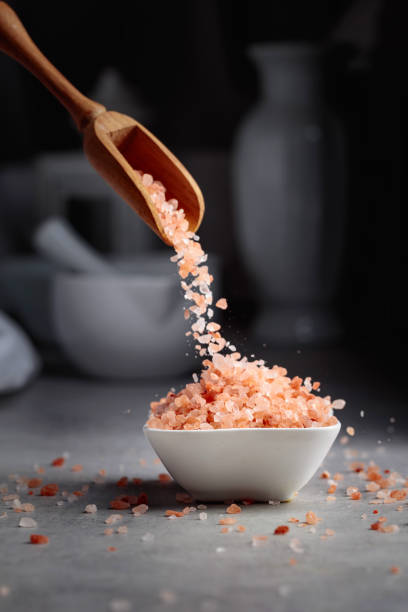 istock Pink salt in crystals is poured into a small white bowl. 1404341122