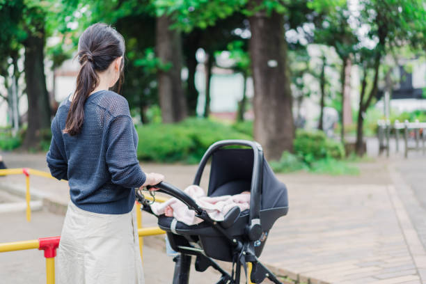 una mamá empujando un cochecito con una sonrisa - cochecito para niños fotografías e imágenes de stock