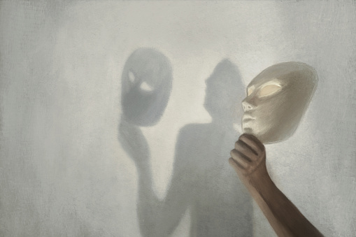 surreal shadow on the wall of a person who takes off the mask from his face, concept of truth and fiction