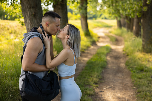 Caucasian young couple, kissing int he nature, before or after their workout