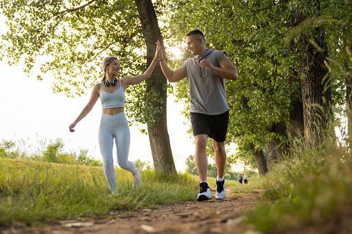Caucasian young couple, together exercising in the nature, while jogging