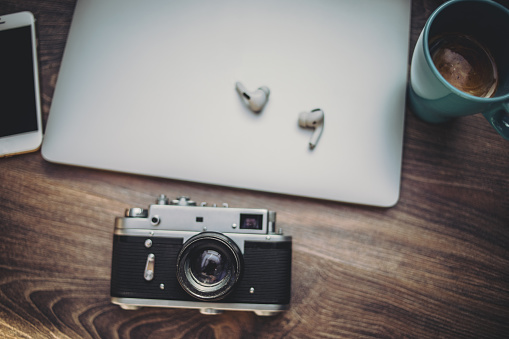 Coffee, laptop, headphones, mobile phone and camera on a wooden surface