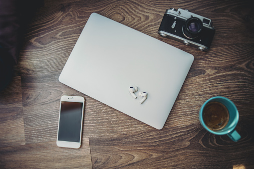 Coffee, laptop, headphones, mobile phone and camera on a wooden surface