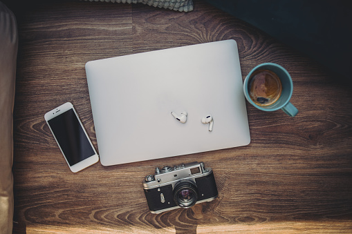 Coffee, laptop, headphones, mobile phone and camera on a wooden surface