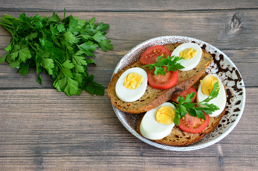 healthy sandwiches with wholegrain bread, eggs and tomatoes on wooden background