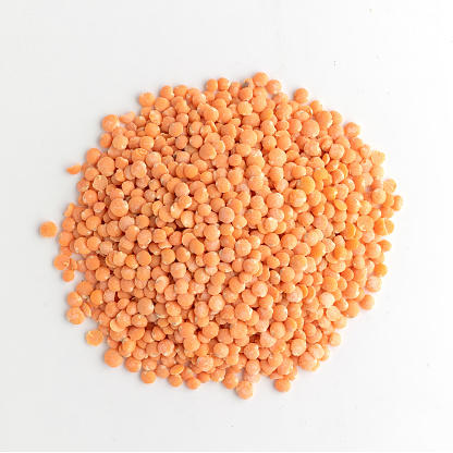 Red lentils on a wooden spoon - isolated oon white