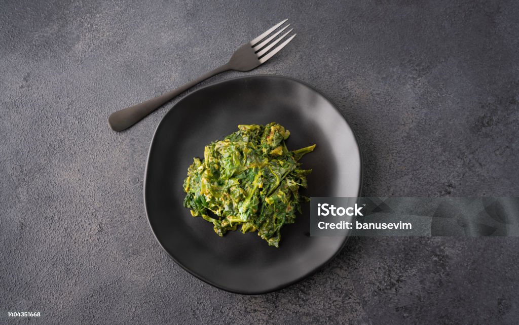 Spinach with egg on black plate Salad Stock Photo