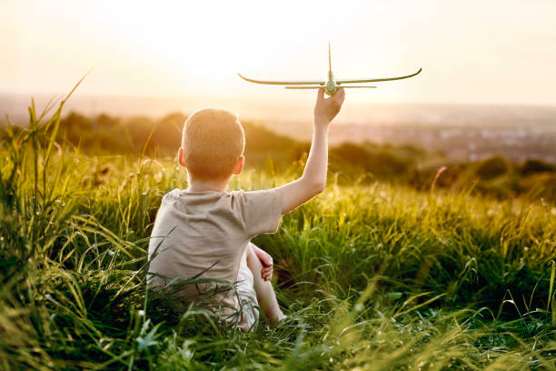 istock Little boy sitting on the meadow with toy airplane 1404353454