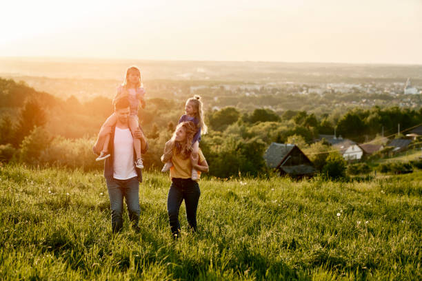 istock Family with two daughters walking at the meadow during the sunset 1404353494