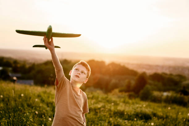 istock Ginger boy holding toy airplane on the meadow 1404353669