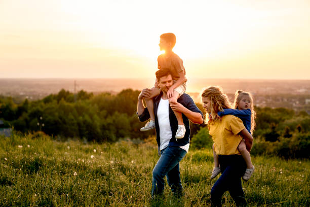 istock Family with two daughters walking at the meadow during the sunset 1404353751