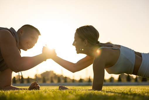 Caucasian young couple, together exercising in the nature during sunset