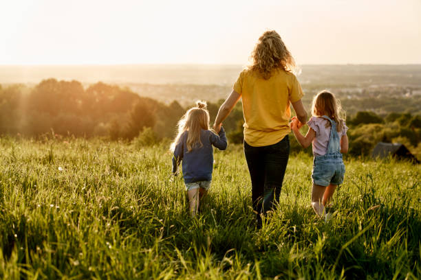 istock Rear view of mom with two daughters walking at the meadow 1404353979