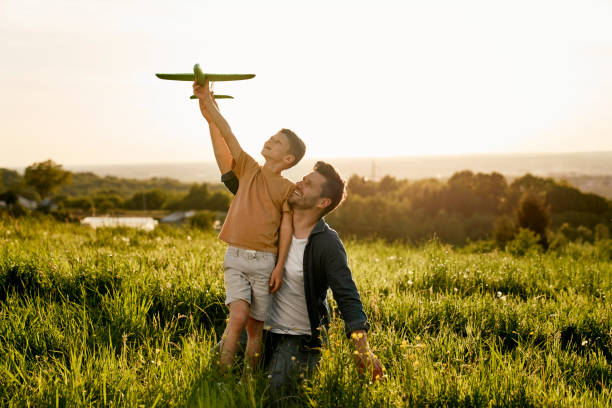 istock Little boy with father playing a toy airplane at meadow 1404354498