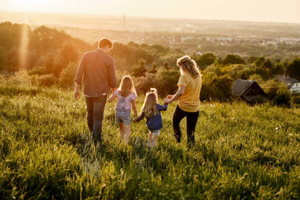 Rear view of family with two daughters walking at the meadow stock photo