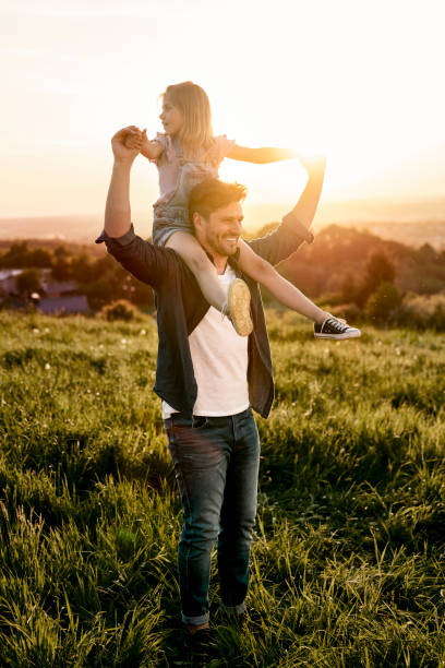 istock Father with daughter walking at the meadow during the sunset 1404355615