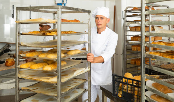 istock Male baker carrying rack trolley with bread 1404355809