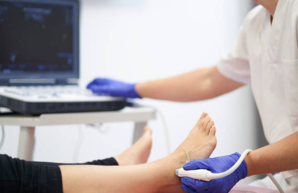 a physiotherapist performing an ultrasound on the ankle to check for injury stock photo