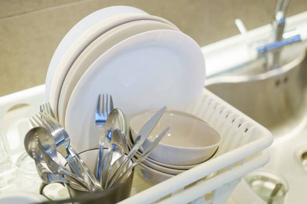 Plates, bowls and silverware on drying rack at the kitchen stock photo