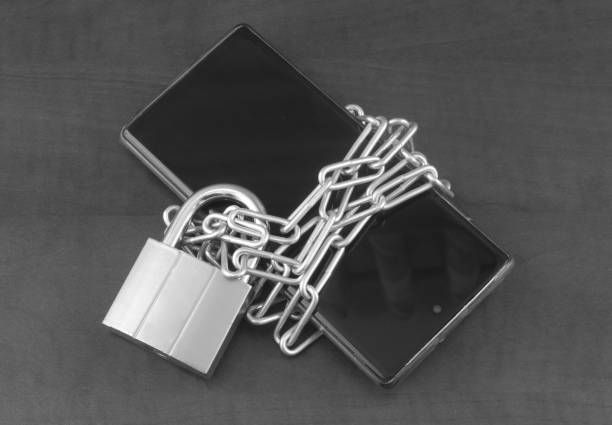 istock Chained smartphone with padlock on wooden background. 1404366995
