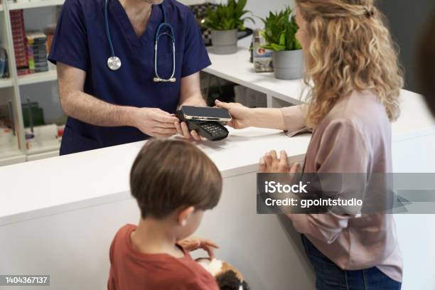 Woman With Child Paying For Helping Their Guinea Pig Stock Photo - Download Image Now
