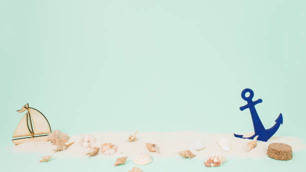 istock Bright sea sand decorated with shells, anchor and boat on pastel green background. Minimal summer concept. Perfect summer party or peaceful ocean aesthetic with copy space. 1404367325