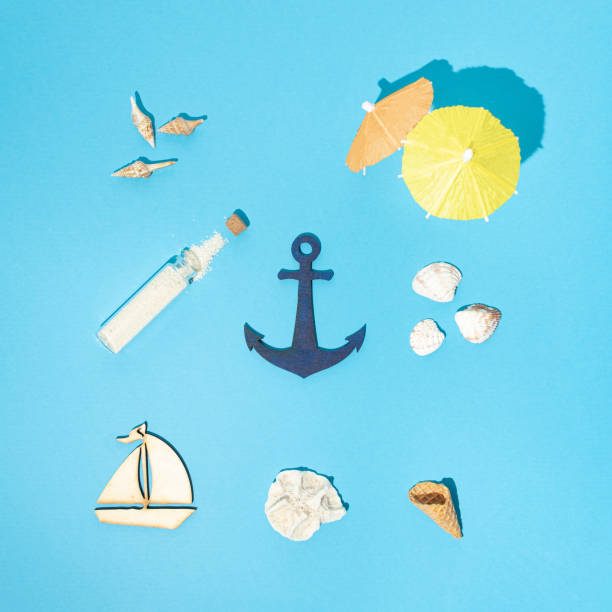 Photo of Minimal pattern made of seashells, ice cream cone, boat, anchor, sand, parasol. Minimal flat lay summer concept on bright blue background. Creative tropical vacation season mood for summer.