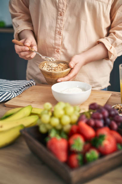 istock Woman adding muesli into the bowl with yogurt 1404368545