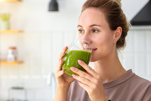 Healthy lifestyle, diet, weight loss concept. Portrait of woman drinking green smoothie close-up. Healthy food, breakfast. Vegetarian, vegan food
