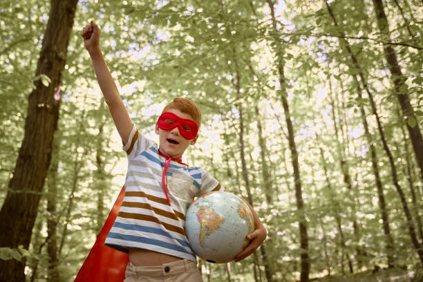 Ginger caucasian boy wearing superhero costume celebrate with globe