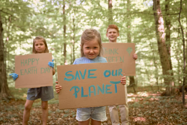 istock Group of kids holding posters and looking at camera in forest 1404370628