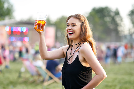 Woman with a glass of beer making toast on music festival
