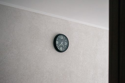 Round clock with arrows on a white wall. Space for inscription. Quality image for your project