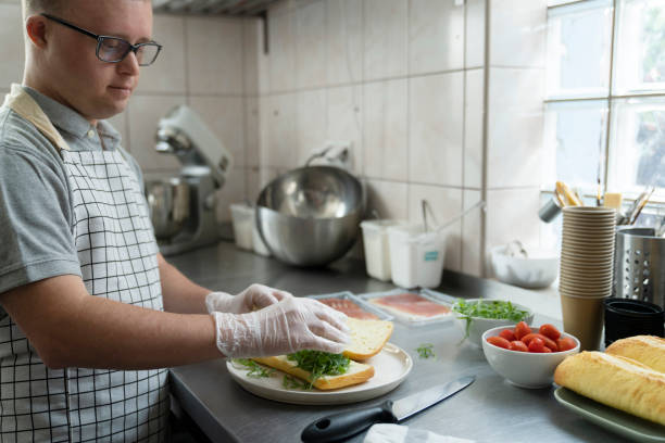 istock Caucasian man with down syndrome preparing a sandwich in commercial kitchen 1404377251