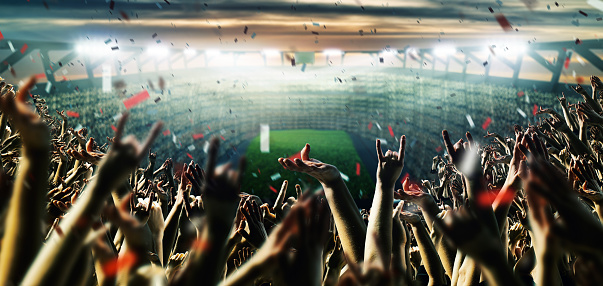 Football or soccer fans are cheering for their team at the stadium on the match