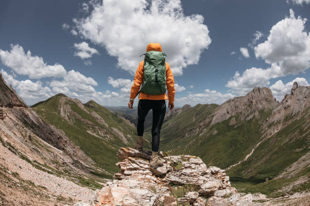 istock Successful woman backpacker hiking on sunset alpine mountain peak 1404380827