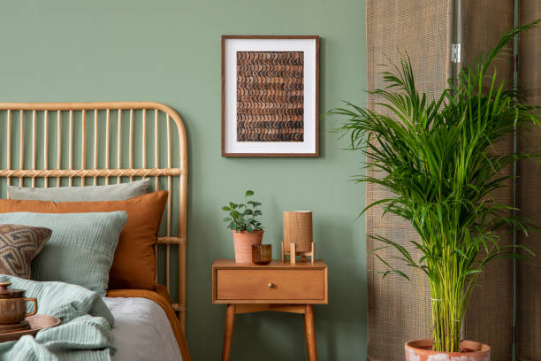 istock Stylish bedroom interior design with mock up poster frame, bamboo bed, night table, plants, folding screen and creative home accessories. Eucalyptus wall. Template. 1404381861