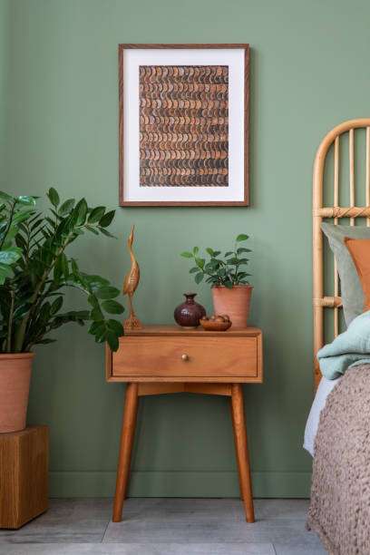 istock Stylish bedroom interior design with mock up poster frame, bamboo bed, night table, plants, folding screen and creative home accessories. Eucalyptus wall. Template. 1404381894