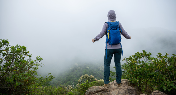 Successful hiker enjoy the view on mountain top cliff edge