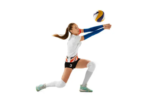 Photo of Female professional volleyball player in sports uniform training with ball isolated on white background. Action, sport, healthy lifestyle, team, fitness concept