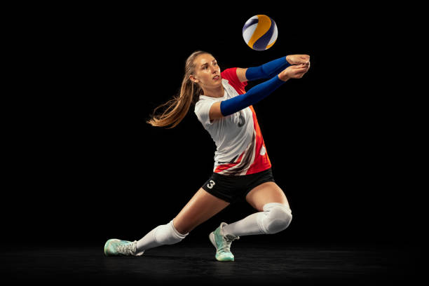 retrato dinâmico de jogador profissional de vôlei em uniforme esportivo jogando vôlei isolado em fundo escuro. esporte, estilo de vida saudável, equipe, ação, conceito de movimento - isolated volleyball women adult - fotografias e filmes do acervo