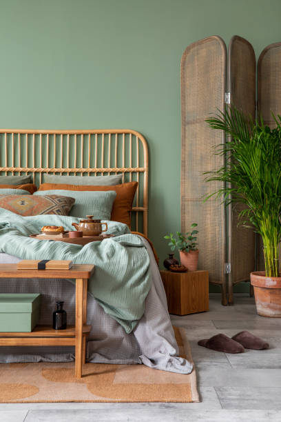 istock Stylish composition of modern bedroom interior. Bed, elegant bedclothes, folding screen and creative personal accessories. Eucalyptus wall. Template. Copy space. 1404384124