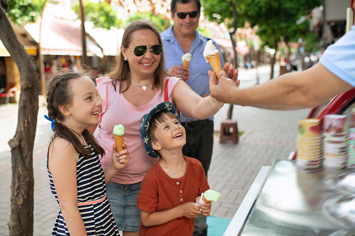 A little boy in a hat is holding an ice cream and looks happy and surprised. Children with ice cream. Summer food and summer time.