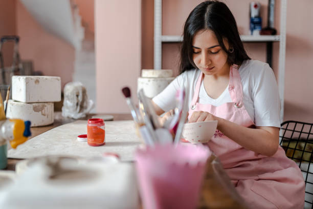 istock Beautiful young woman is painting a ceramic mug in workshop 1404385440