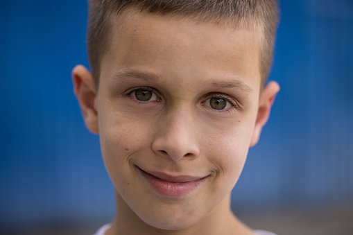 Headshot of cheerful Caucasian boy in front of the blue background