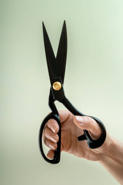 istock Open tailor's scissors in a female hand on a neutral background. Close-up 1404389920