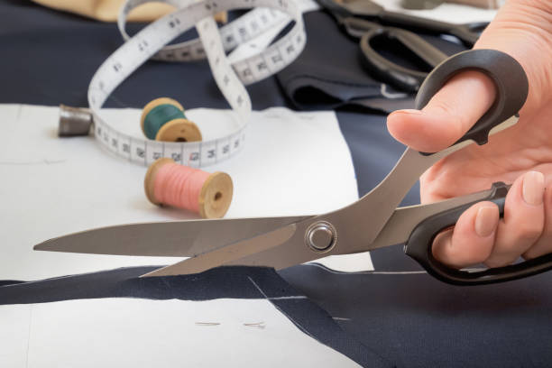 istock Tailor's scissors in a woman's hand cut the fabric according to paper patterns. Close-up 1404390013