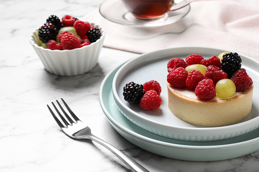 Delicious tartlet with berries on white marble table