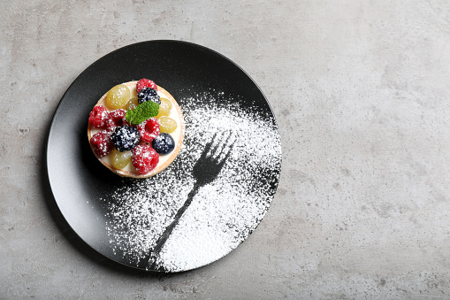 Delicious tartlet with berries on light grey table, top view