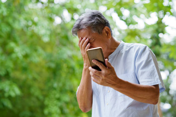 Sad senior man using smartphone. stock photo